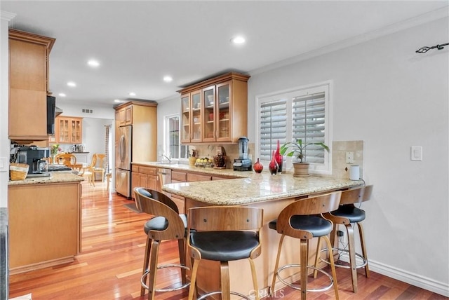 kitchen with stainless steel appliances, crown molding, light wood-type flooring, and kitchen peninsula