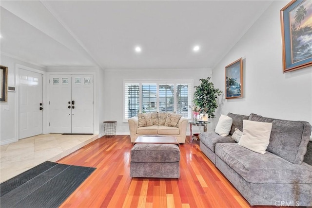 living room with lofted ceiling, wood-type flooring, and ornamental molding