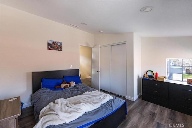 bedroom featuring dark hardwood / wood-style flooring, vaulted ceiling, and a closet