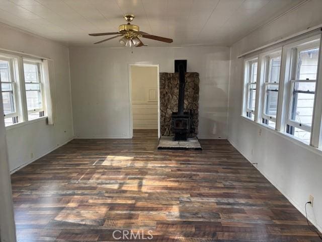 unfurnished living room with dark hardwood / wood-style floors, ceiling fan, and a wood stove