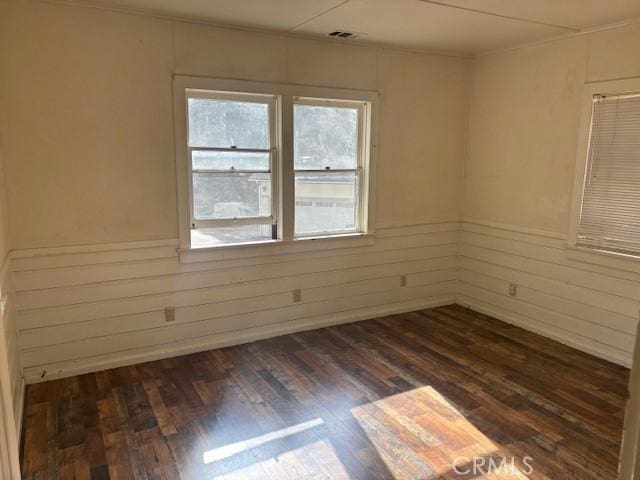 spare room with dark hardwood / wood-style floors and wooden walls