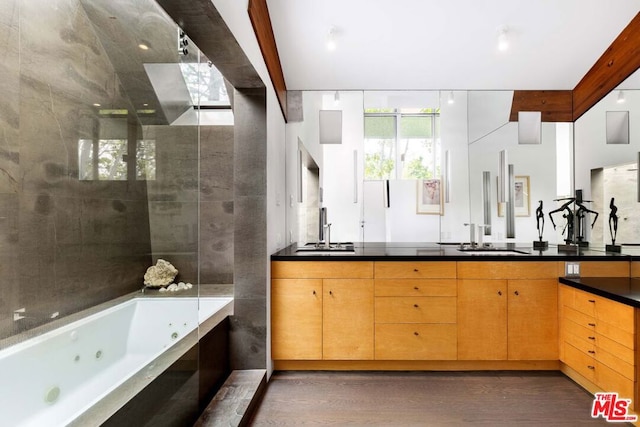 bathroom featuring vanity, a relaxing tiled tub, and wood-type flooring