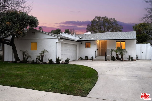 ranch-style home with a garage and a yard