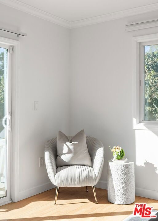 sitting room featuring wood-type flooring, ornamental molding, and a wealth of natural light