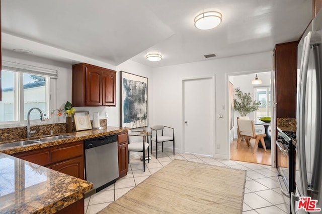 kitchen featuring light tile patterned flooring, pendant lighting, sink, dark stone counters, and stainless steel appliances