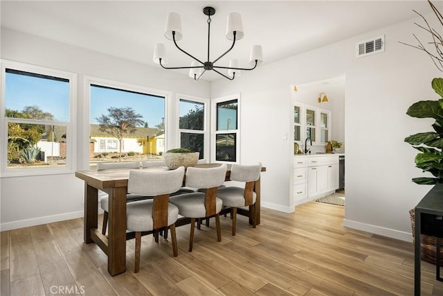 dining space featuring a chandelier, plenty of natural light, visible vents, and light wood-style floors