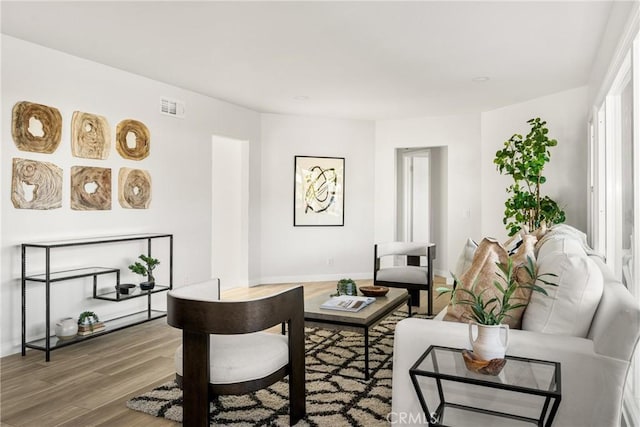 living room featuring visible vents, baseboards, and wood finished floors