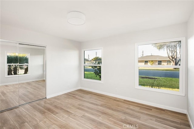 interior space with baseboards, light wood finished floors, and a healthy amount of sunlight