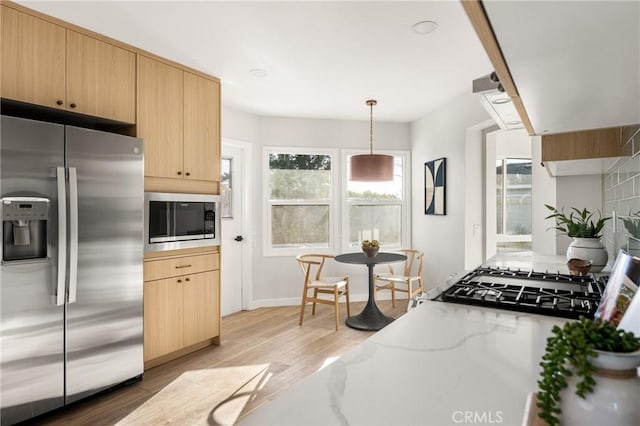 kitchen featuring stainless steel fridge with ice dispenser, decorative light fixtures, light stone countertops, built in microwave, and light brown cabinets