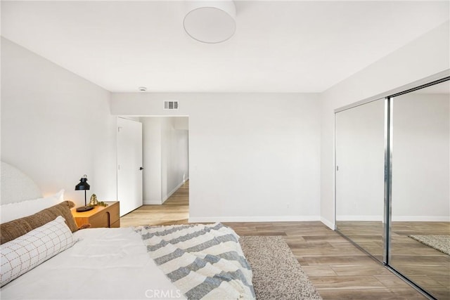 bedroom featuring baseboards, a closet, visible vents, and light wood-style floors