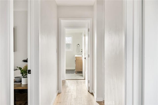 corridor with light wood-type flooring and baseboards