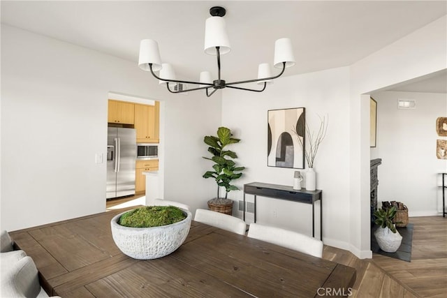 dining room with a chandelier, baseboards, and wood finished floors