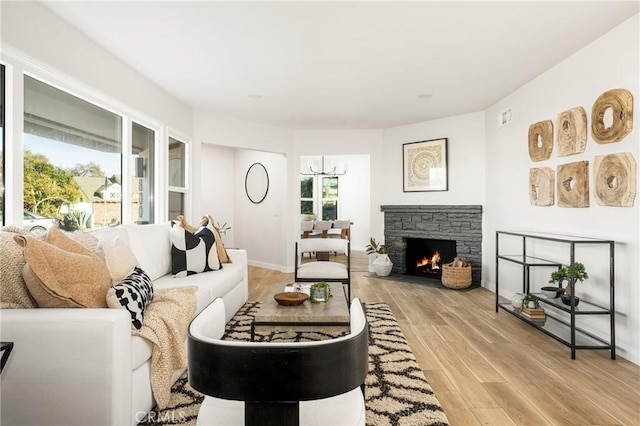 living area featuring baseboards, a stone fireplace, and light wood-style floors