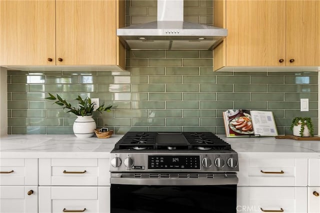 kitchen featuring white cabinets, stainless steel gas stove, wall chimney exhaust hood, and light stone countertops