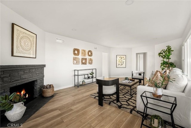 living area featuring light wood-style floors, a fireplace, and baseboards