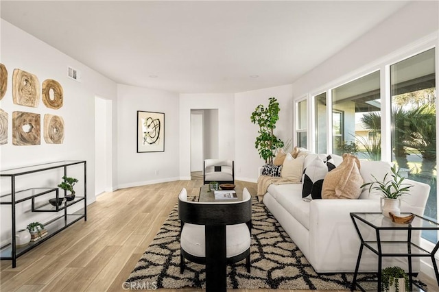 living area featuring baseboards, visible vents, and light wood-style floors