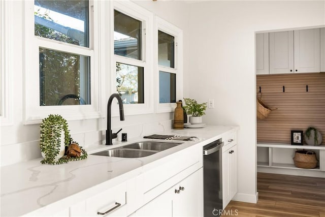 kitchen featuring light stone countertops, white cabinets, a sink, and wood finished floors