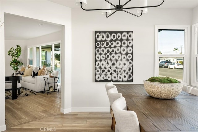 dining space featuring light wood-style flooring, baseboards, and a notable chandelier