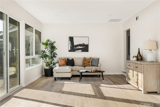 sitting room with visible vents, light wood-style flooring, and baseboards