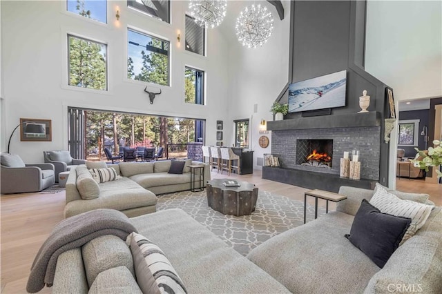 living area featuring a warm lit fireplace, wood finished floors, and a notable chandelier