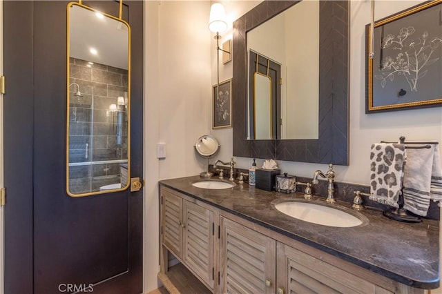 full bathroom featuring a tile shower, double vanity, and a sink