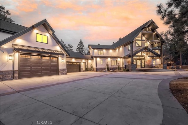 view of front of house featuring metal roof, stone siding, concrete driveway, stucco siding, and a standing seam roof