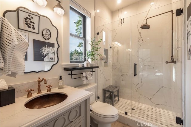 full bathroom featuring toilet, a marble finish shower, and vanity