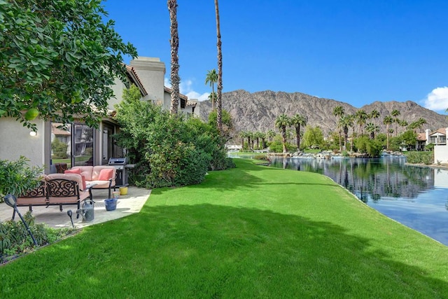 view of property's community with an outdoor hangout area, a water and mountain view, and a lawn