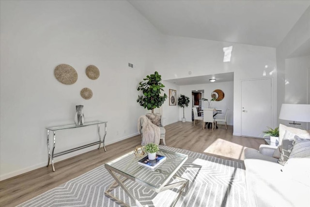 living room with high vaulted ceiling and light wood-type flooring