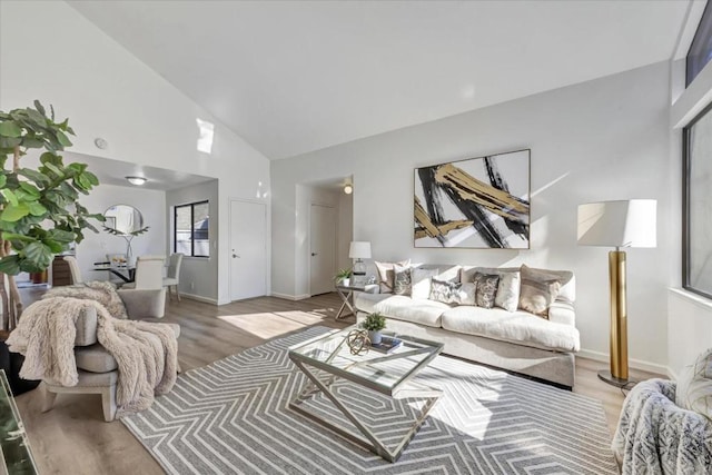 living room with high vaulted ceiling and light wood-type flooring