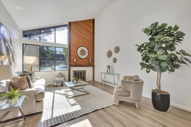 living room with light hardwood / wood-style flooring, a fireplace, and high vaulted ceiling