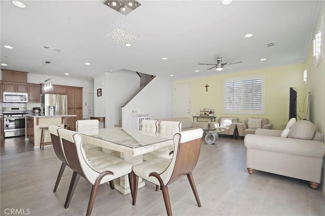 dining space with ornamental molding, light hardwood / wood-style floors, and ceiling fan