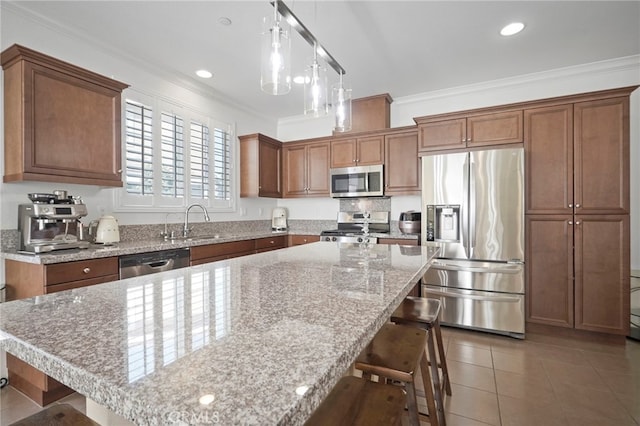 kitchen with appliances with stainless steel finishes, a kitchen breakfast bar, a center island, and sink