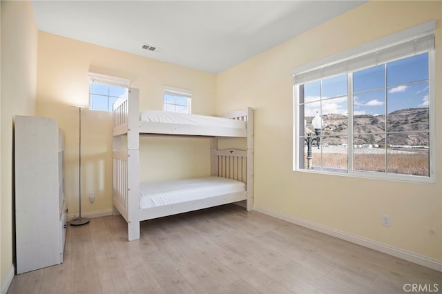 unfurnished bedroom featuring a mountain view and light hardwood / wood-style flooring