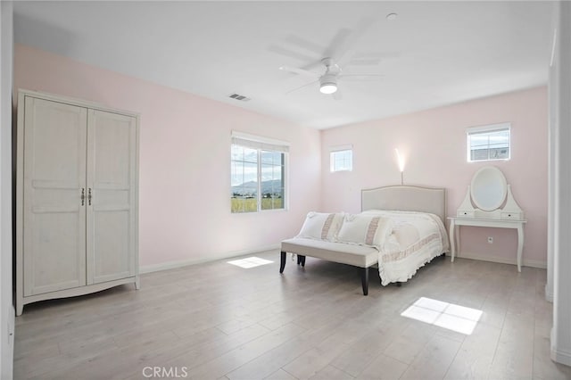 bedroom with multiple windows, ceiling fan, and light hardwood / wood-style floors