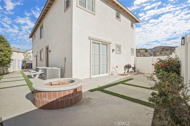 back of house with a patio area, a fire pit, and central air condition unit