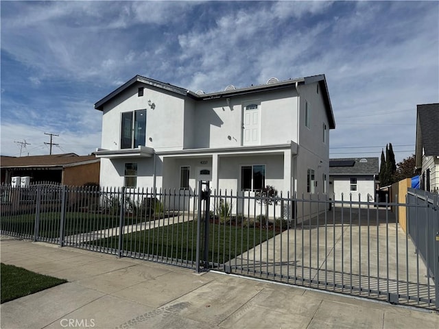 view of front facade with a fenced front yard, concrete driveway, a front lawn, and stucco siding