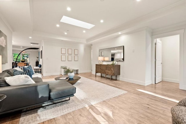 living room with a skylight, wood-type flooring, crown molding, and a tray ceiling