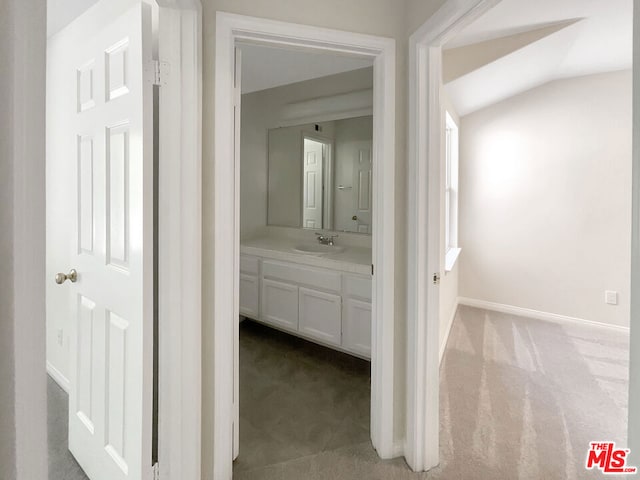 hallway with carpet, sink, and lofted ceiling