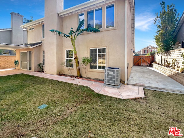 rear view of property with central AC, a patio area, and a lawn