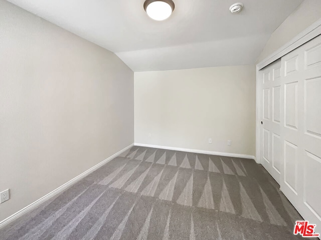 additional living space featuring vaulted ceiling and dark colored carpet