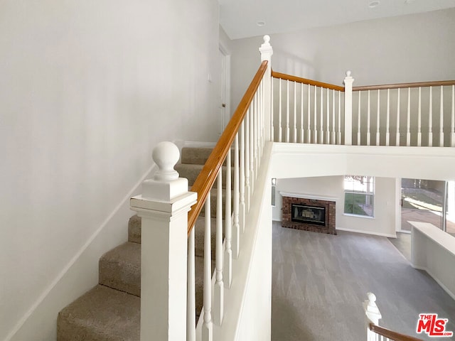 stairway with a towering ceiling and a fireplace