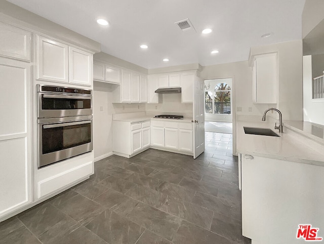 kitchen featuring white cabinetry, appliances with stainless steel finishes, sink, and light stone counters