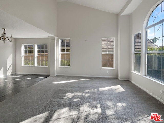 empty room with an inviting chandelier, high vaulted ceiling, and decorative columns