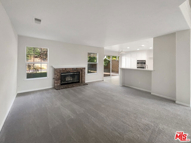 unfurnished living room with carpet and a brick fireplace