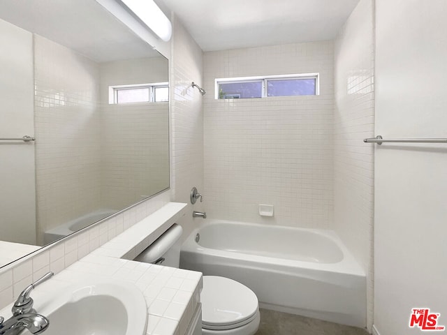 full bathroom featuring sink, tiled shower / bath, and toilet