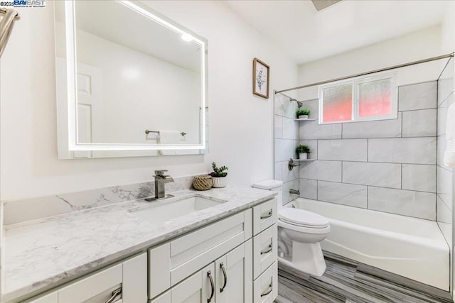 full bathroom with tiled shower / bath, vanity, and toilet