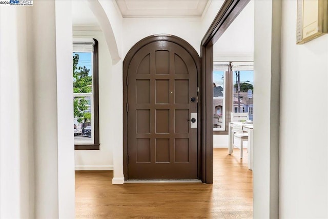 entrance foyer featuring crown molding, plenty of natural light, and light wood-type flooring