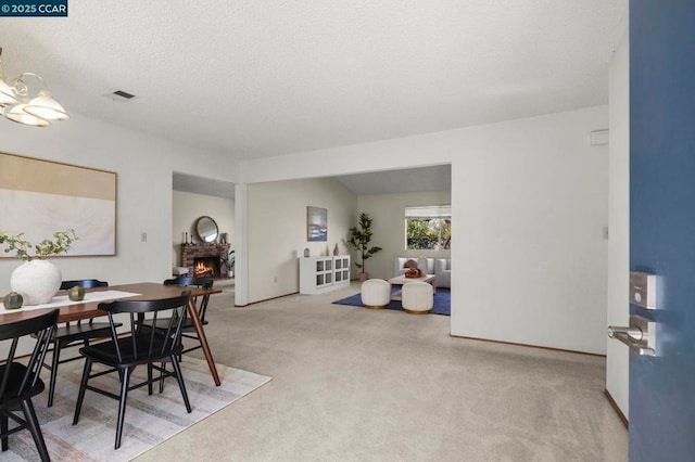 dining space featuring carpet flooring, a fireplace, vaulted ceiling, and a textured ceiling