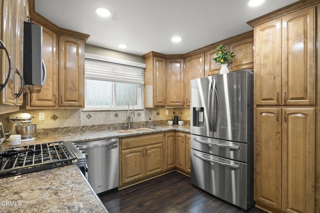 kitchen featuring sink, stainless steel appliances, dark hardwood / wood-style floors, light stone counters, and tasteful backsplash